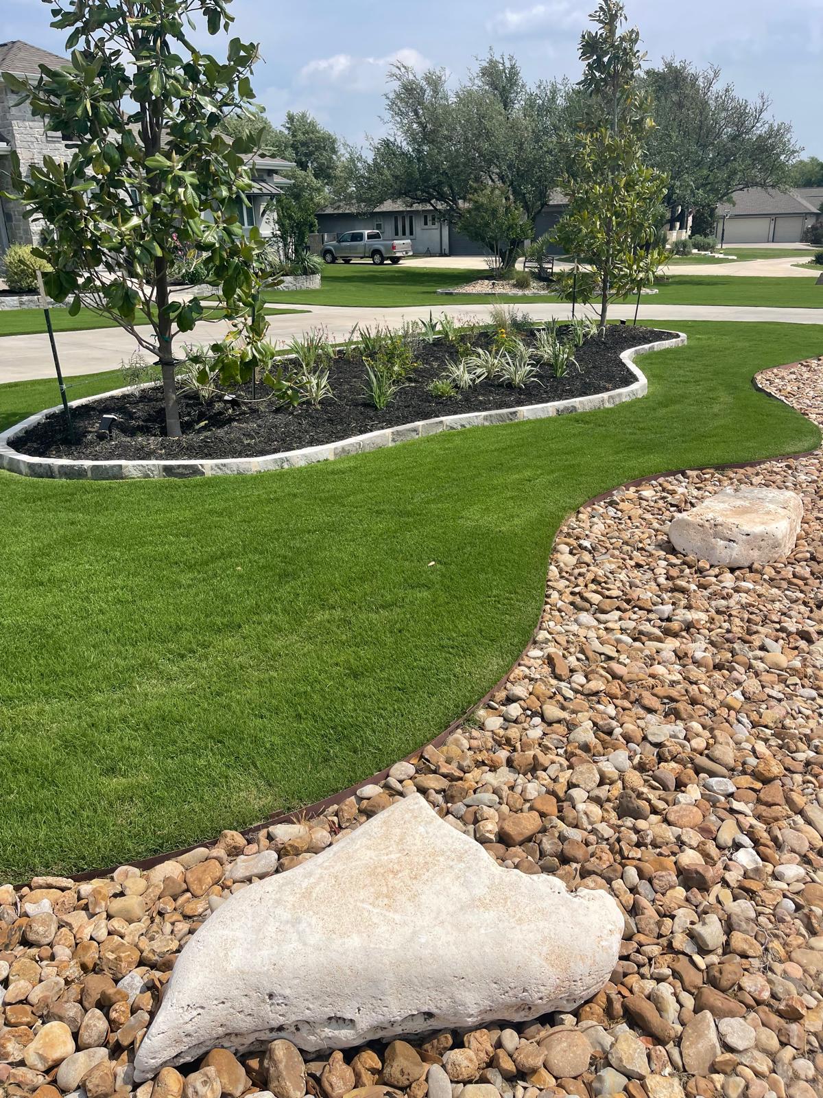 Landscaped flowerbed with stone border and fresh mulch